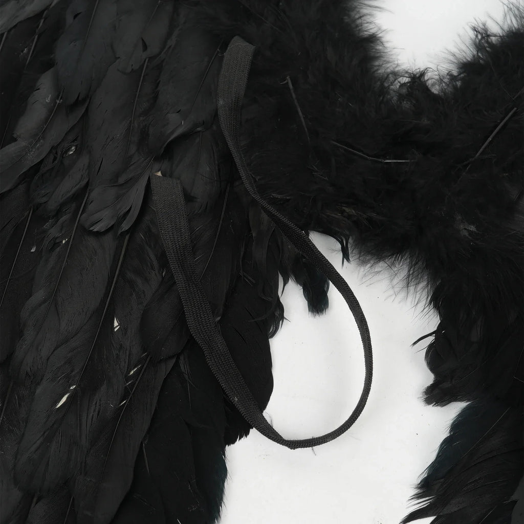 Close-up detail of black elastic straps on the back of black feather angel wings