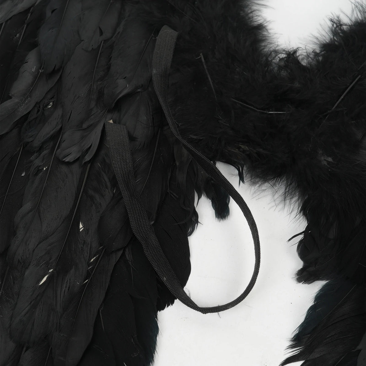 Close-up detail of black elastic straps on the back of black feather angel wings