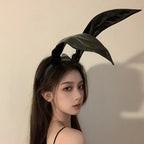 Model wearing shiny black rabbit ear headband, side profile view