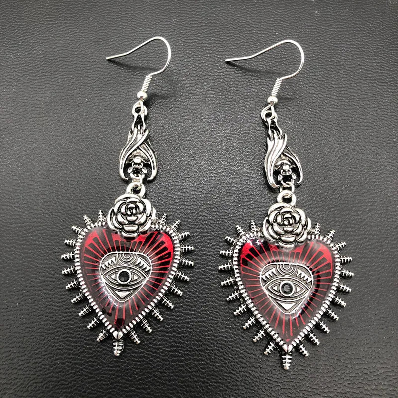 Pair of red evil eye heart earrings with silver rose, front flat lay