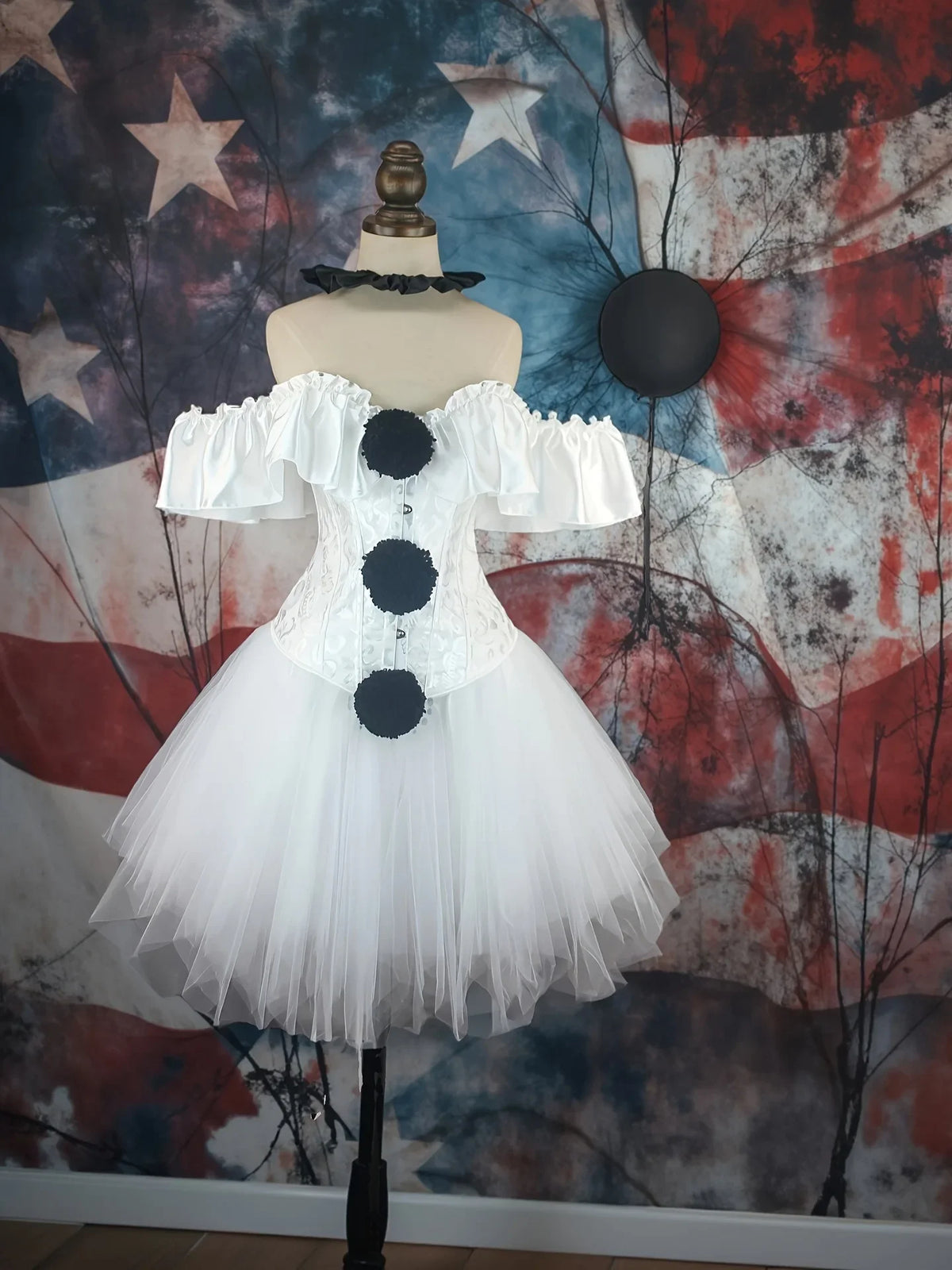 White creepy clown corset costume with black pom poms on mannequin, front view
