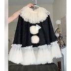 Black velvet pierrot clown poncho with white pom poms and tulle ruffle on hanger, close view