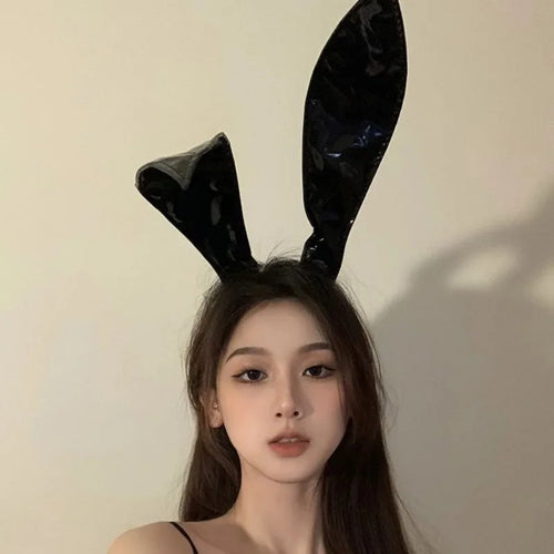 Model wearing shiny black rabbit ear headband, front view