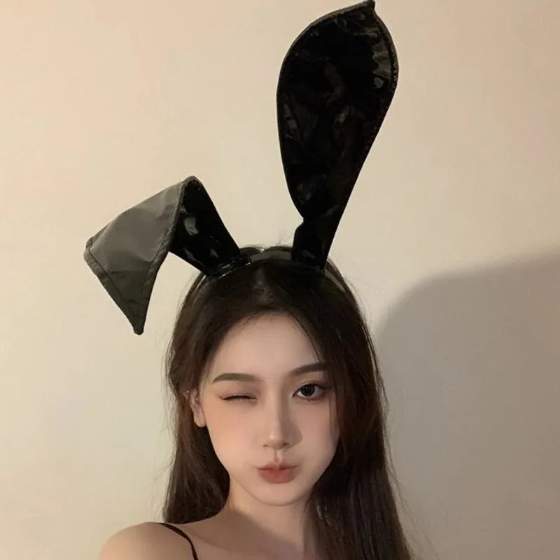 Model winking wearing shiny black rabbit ear headband, front view
