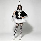 Model in black pierrot poncho with pom pom hat and striped tights, full front view