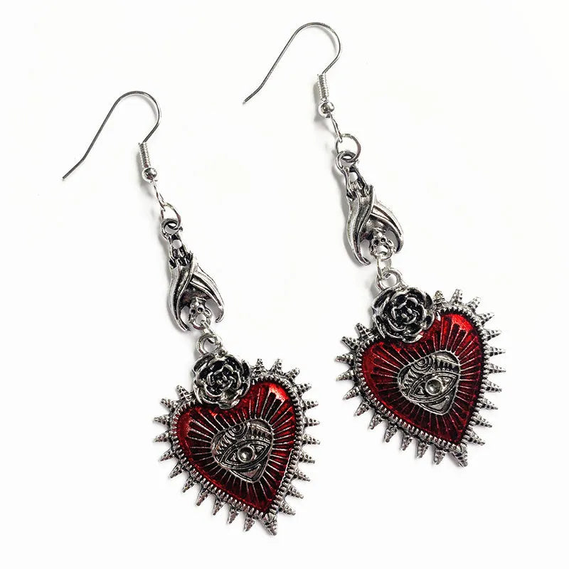 Gothic red heart evil eye earrings with rose and bat details, angled view