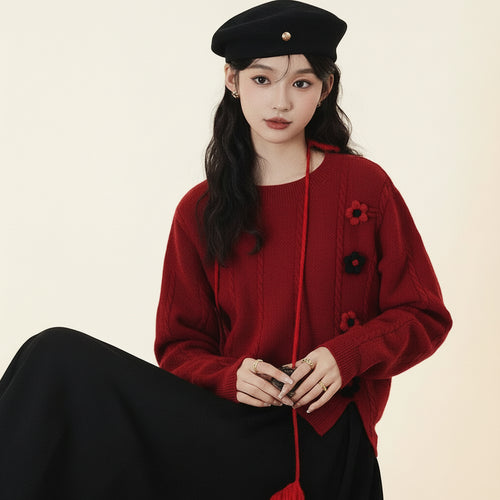 Woman wearing a red college style loose pullover sweater with floral details and a black beret