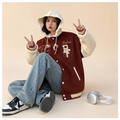 Woman wearing american style oversized blazer women with brown and cream varsity design sitting by a coffee bar