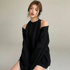 Black loose fit women's sweatshirt with cold shoulder design worn by a seated woman with headphones