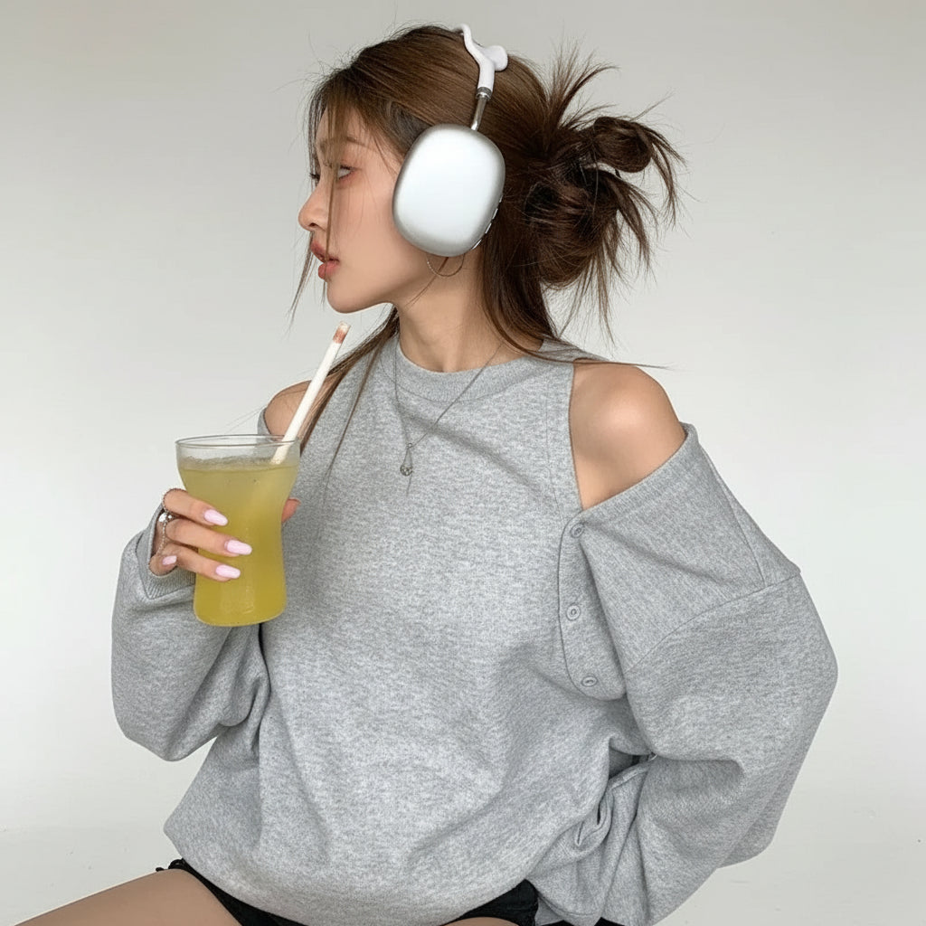 Casual grey sweatshirt worn by woman with headphones drinking yellow juice indoors