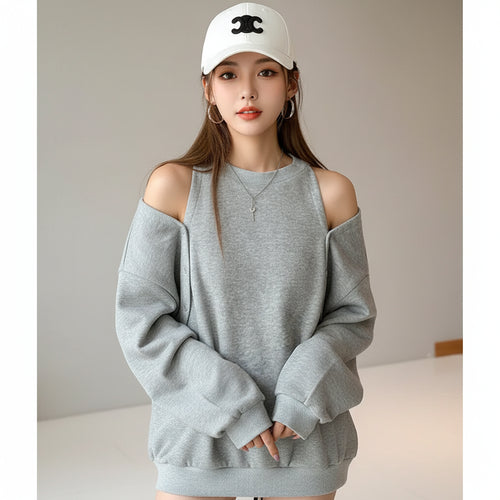 Gray loose fit women's sweatshirt with button shoulder detail worn by model with white cap indoors
