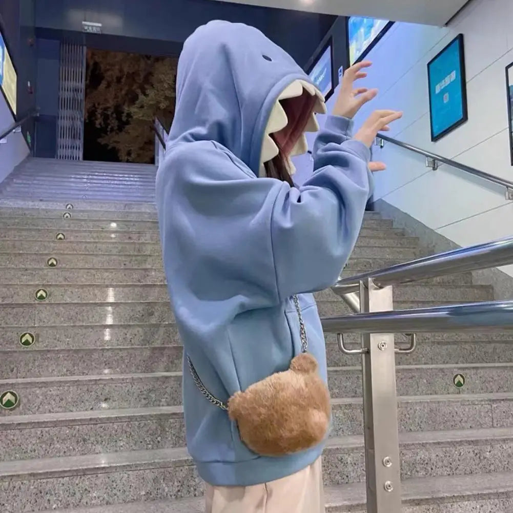 Person wearing oversized shark pullover hoodie in blue with shark teeth hood design on stairs
