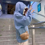 Person wearing oversized shark pullover hoodie in blue with shark teeth hood design on stairs