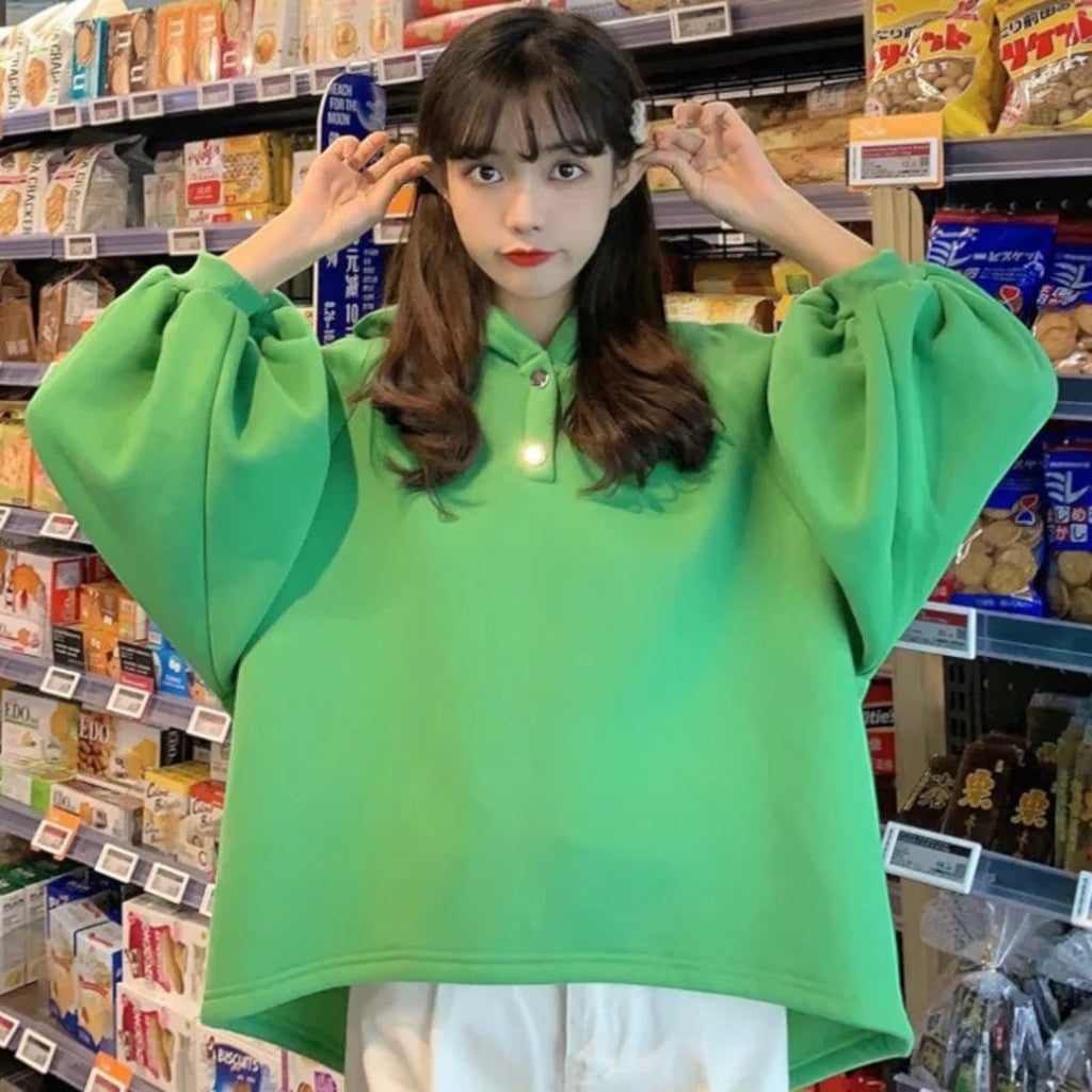 Cartoon dinosaur japanese hoodie for women in bright green with oversized sleeves worn by a young woman