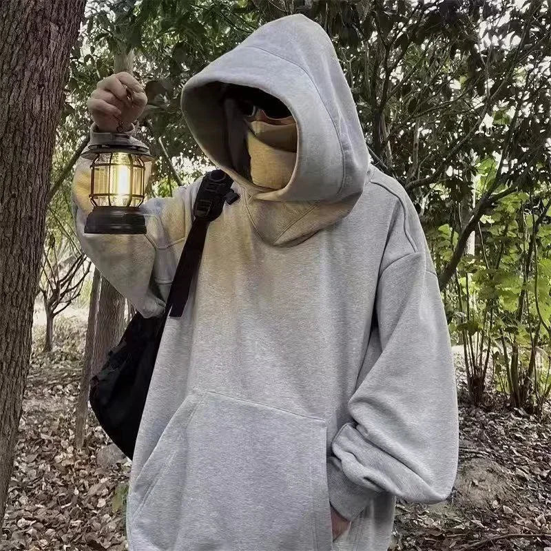 Person wearing casual Japanese streetwear fashion hoodie holding a lantern in a forest setting