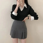 Woman wearing casual knitwear for women black sweater with white collared shirt and gray pleated skirt