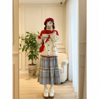 Woman wearing a cute retro apple knitted cardigan with red and cream colors paired with a plaid skirt and red beret