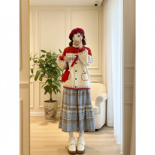 Woman wearing a cute retro apple knitted cardigan with red and cream colors paired with a plaid skirt and red beret