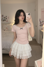 Young Asian woman wearing a pale pink bowknot top and white layered ruffle skirt in a natural bedroom mirror selfie