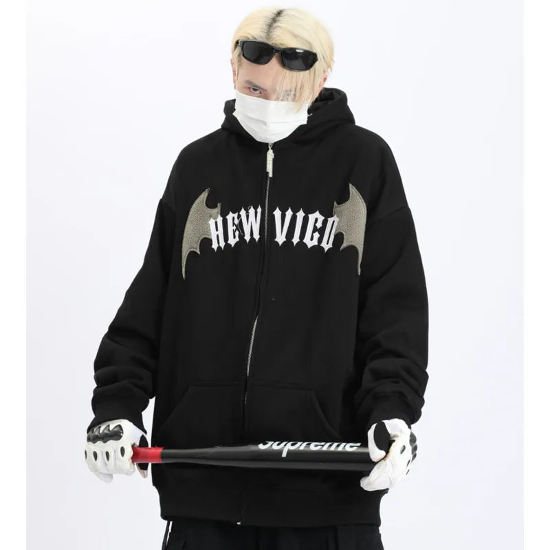 Black japanese devil anime hoodie for couples with wing design worn by person holding baseball bat