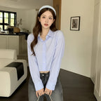 Woman wearing a Korean striped shirt and sweater set with light blue stripes and high-waisted jeans indoors