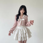Woman wearing a pink bowknot two piece skirt set with long puff sleeves and layered white skirt indoors