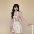 Woman wearing pink bowknot two piece skirt set with long sleeves and layered white skirt indoors
