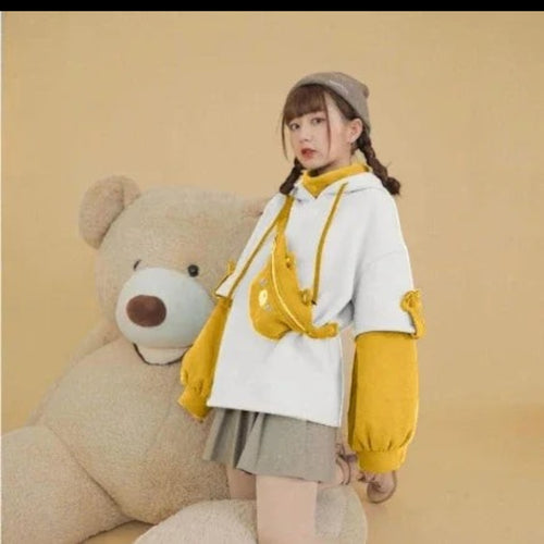 Young woman wearing kawaii bear anime Crewneck Long Sleeve hoodie in white and yellow posing with large teddy bear