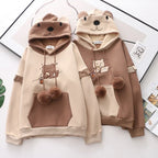 Two kawaii bear japanese hoodie for women in beige and brown with bear face hoods and pom pom drawstrings