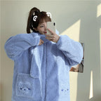 Woman wearing a light blue kawaii fluffy jacket for women with bear patch pockets taking a selfie