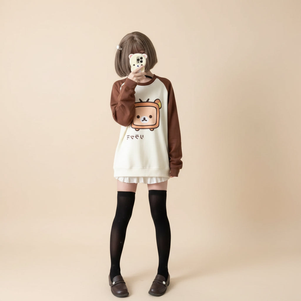 Cute Japanese kawaii pullover top with brown sleeves and bear graphic worn with black thigh-high socks