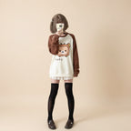 Cute Japanese kawaii pullover top with brown sleeves and bear graphic worn with black thigh-high socks