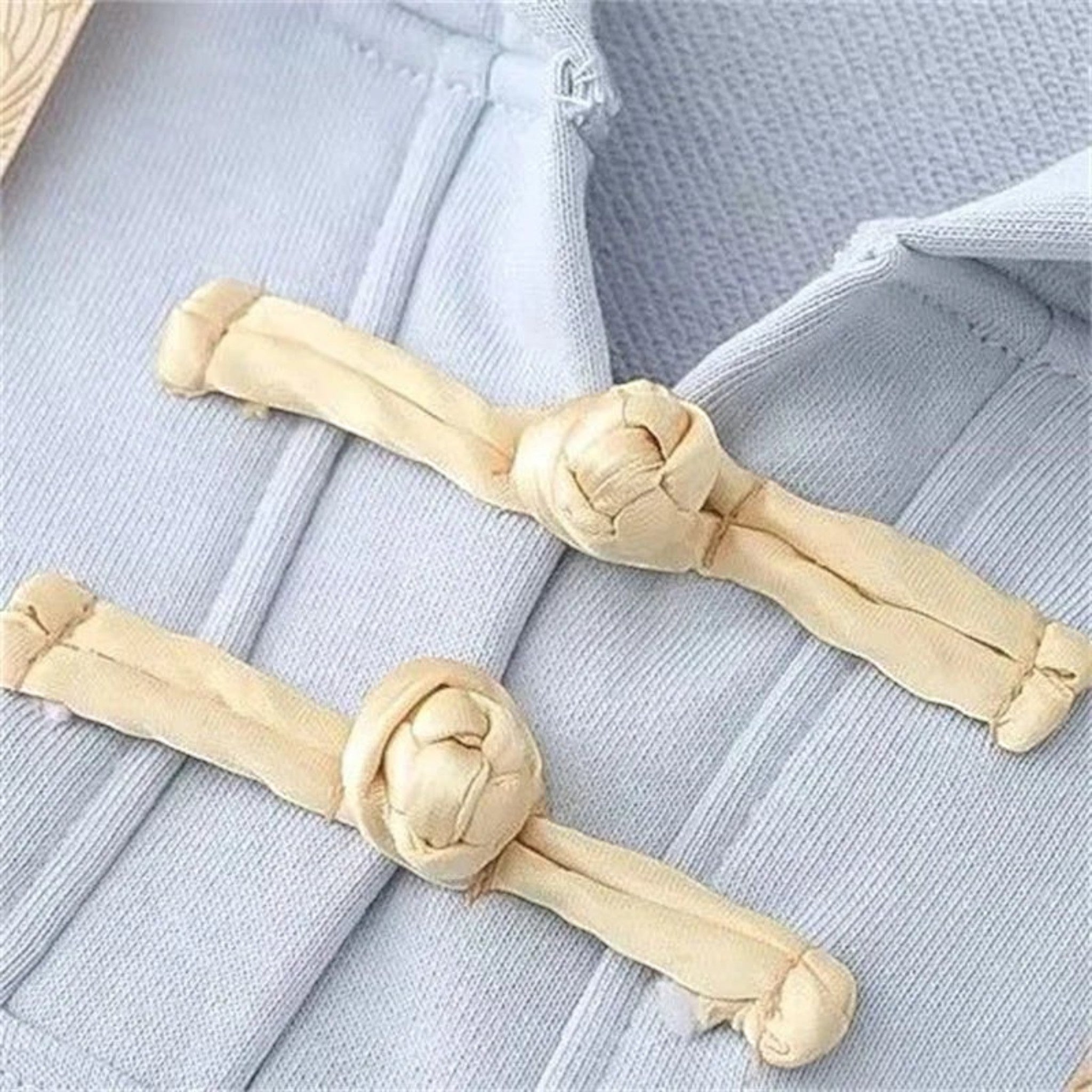 Close-up detail of beige button knots on a light blue kawaii loose long sleeve spring hoodie
