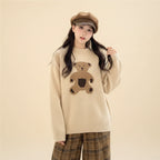 Woman wearing a beige kawaii style bear sweater for women with a brown bear design sitting outdoors