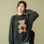 Woman wearing a dark gray kawaii style bear sweater for women with a cute bear design in a cozy cafe