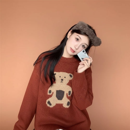 Woman wearing a kawaii style bear sweater for women in brown with bear graphic sitting indoors