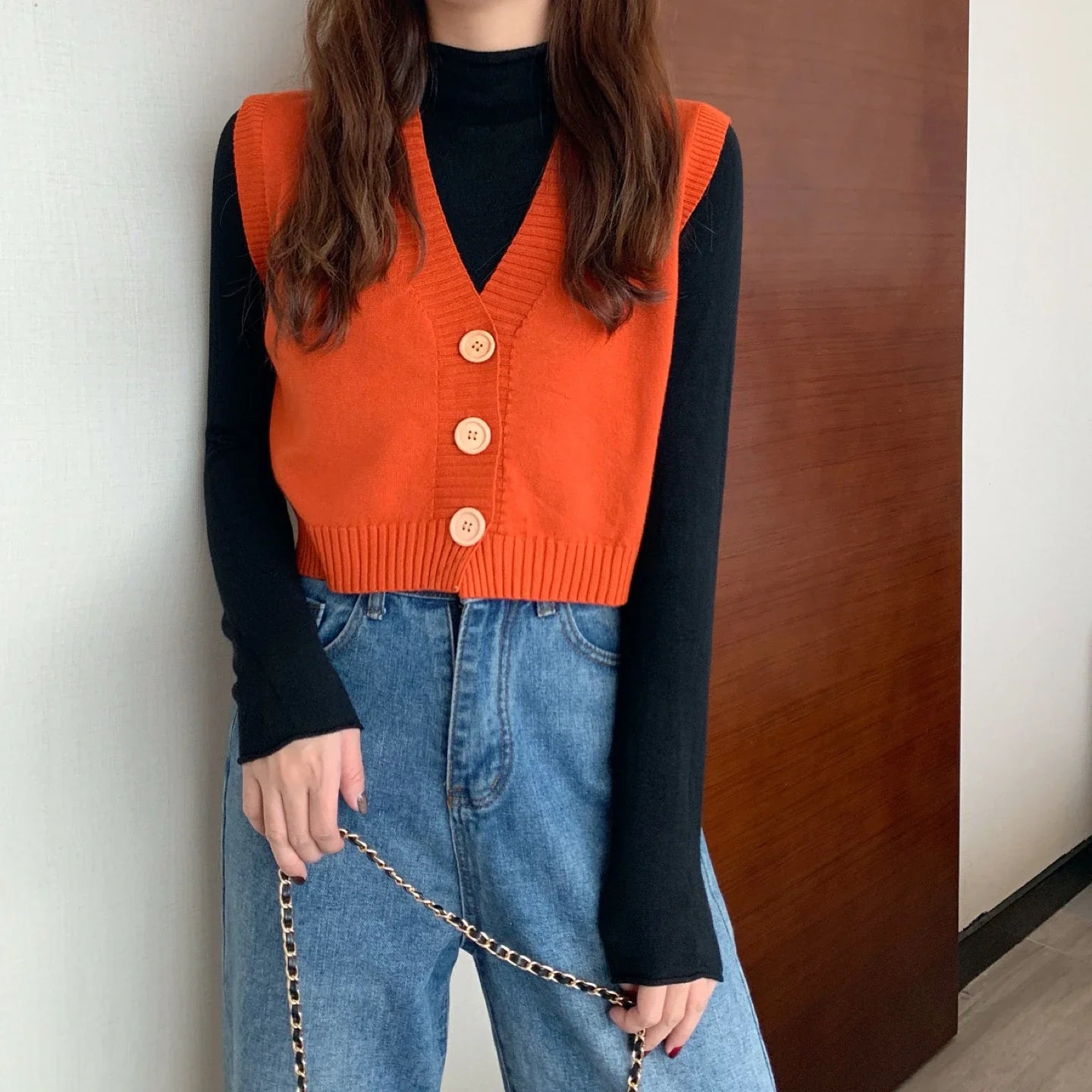 Korean fashion crop knit top in orange with buttons, paired with a black long-sleeve shirt and blue jeans
