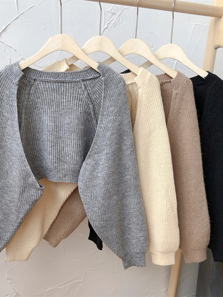 Collection of Korean knitted short cardigans in various colors hanging on a wooden rack