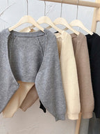 Collection of Korean knitted short cardigans in various colors hanging on a wooden rack