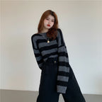 Woman wearing a black and gray Korean striped knit sweater paired with high-waisted black pants indoors