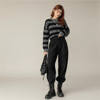 Woman wearing black and gray Korean striped knit sweater with high-waisted black pants and black boots