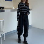 Woman wearing a Korean striped knit sweater in black and gray paired with black pants and boots