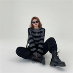 Woman wearing a Korean striped knit sweater in black and gray with black pants and boots sitting on the floor