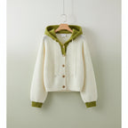 White and green korean style cardigan sweater with hood and button front laid on beige couch