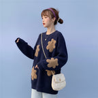 Woman wearing Korean style loose bear jumper in navy with teddy bear patches and white handbag outdoors