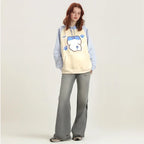 Woman wearing kuromi print kawaii sweatshirt with blue sleeves and paw prints paired with gray pants