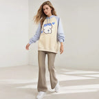 Woman wearing kuromi print kawaii sweatshirt with cream and light blue color blocking and paw print design