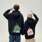 Matching couple hoodies with cartoon design featuring cute pink and green dinosaurs on black hoodies