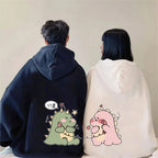 Matching couple hoodies with cartoon design featuring cute green and pink dinosaurs on black and white hoodies