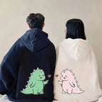 Matching couple hoodies with cartoon design featuring cute green and pink dinosaur characters on back